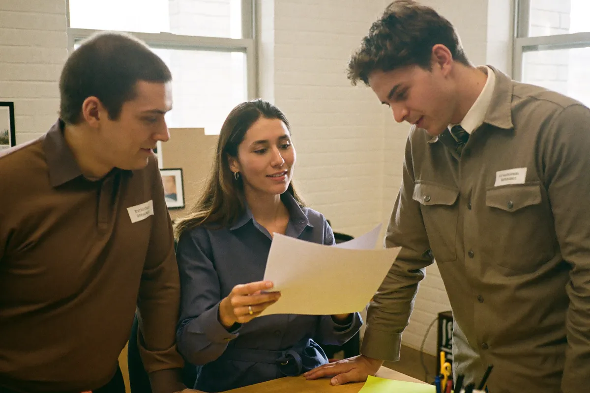 Three colleagues reading a printed page together at a desk